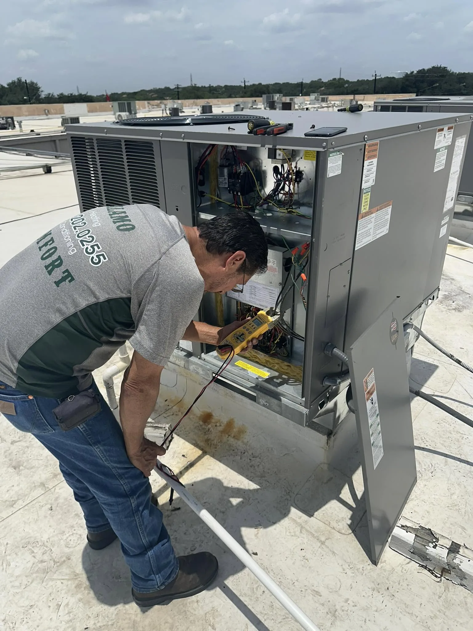 Alamo Comfort technician running diagnostics on a rooftop HVAC unit in San Antonio